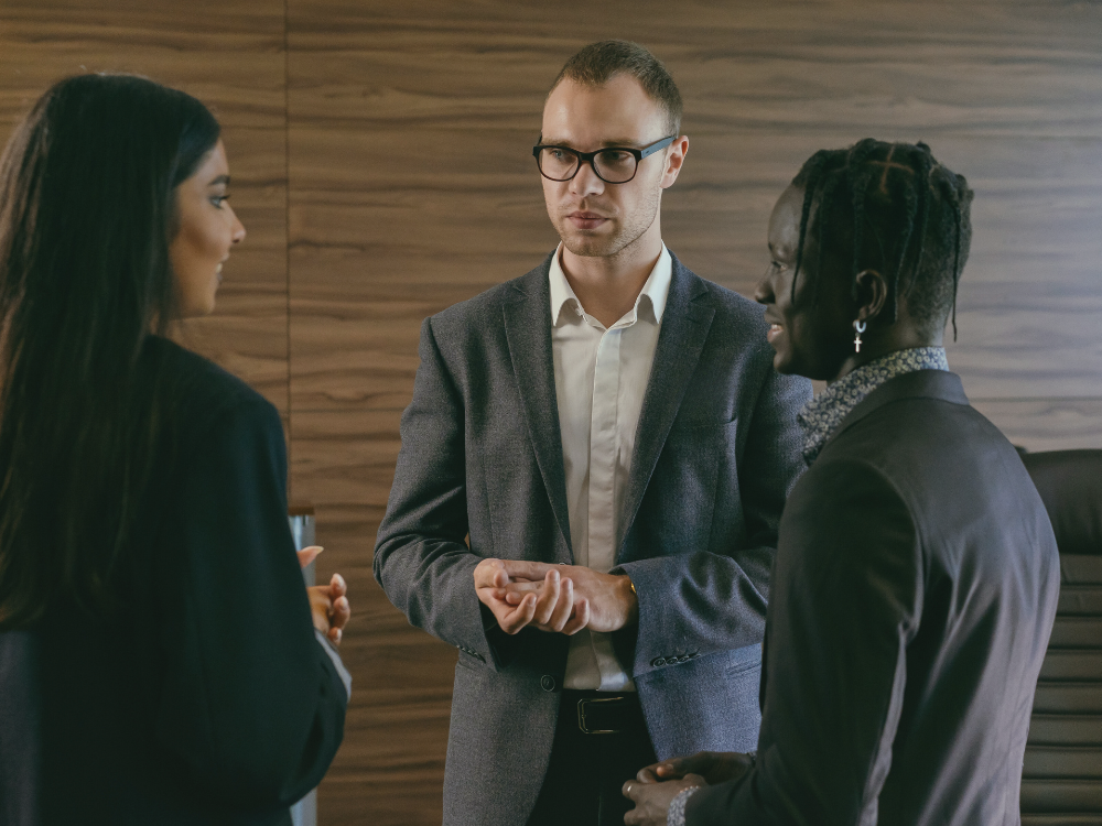 Two women and one man talking in an office.
